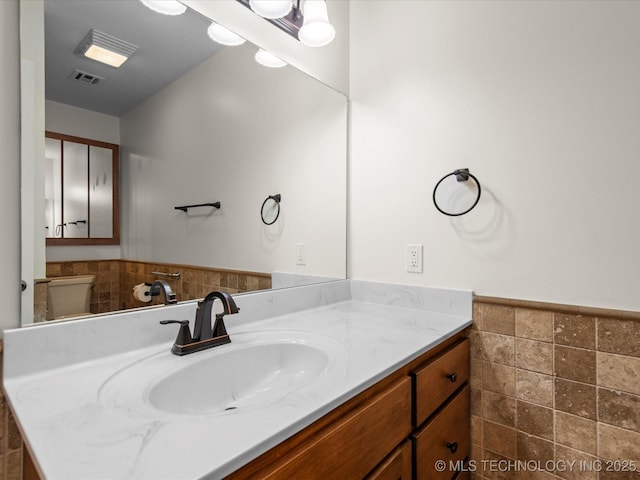 1044 Meadow Dr, Bartlesville, OK 74006 - bathroom featuring tile walls, wainscoting, vanity, and toilet