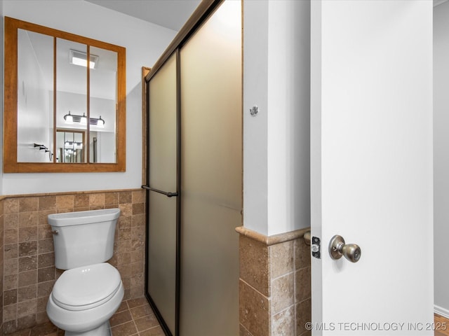 1044 Meadow Dr, Bartlesville, OK 74006 - bathroom with tile walls, a wainscoted wall, a stall shower, toilet, and tile patterned flooring