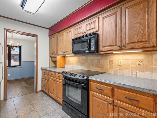 1044 Meadow Dr, Bartlesville, OK 74006 - kitchen with black appliances, a chandelier, and brown cabinets