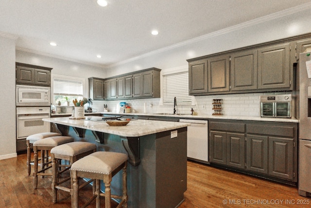 7646 S Fulton Ave, Tulsa, OK 74136 - kitchen featuring white appliances, a sink, a center island, a kitchen breakfast bar, and tasteful backsplash