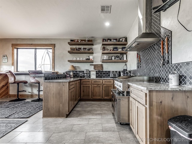29550 S 4240th Rd, Inola, OK 74036 - kitchen featuring open shelves, wall chimney range hood, decorative backsplash, a peninsula, and a kitchen breakfast bar