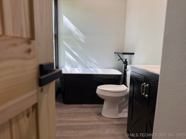 618 E Gentry Ave, Checotah, OK 74426 - full bath featuring wood finished floors, a soaking tub, toilet, and vanity