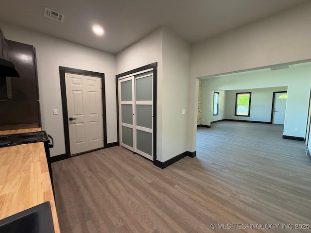 618 E Gentry Ave, Checotah, OK 74426 - kitchen with wood finished floors, butcher block counters, baseboards, recessed lighting, and under cabinet range hood
