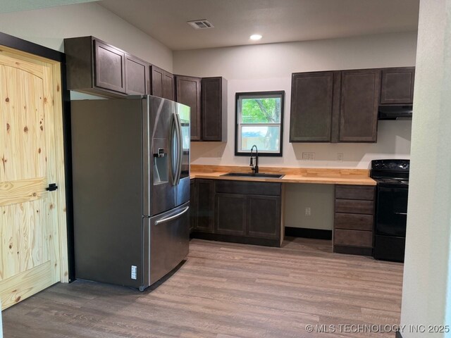 618 E Gentry Ave, Checotah, OK 74426 - kitchen with stainless steel fridge with ice dispenser, black / electric stove, under cabinet range hood, a sink, and light wood-type flooring