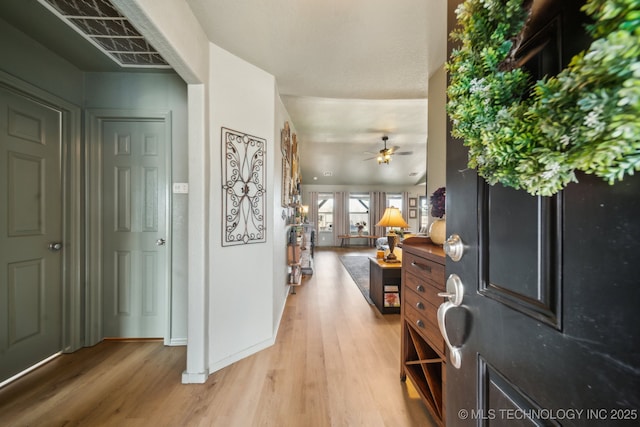 entryway with light wood finished floors, ceiling fan, and baseboards
