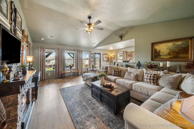 living area with ceiling fan, vaulted ceiling, and wood finished floors