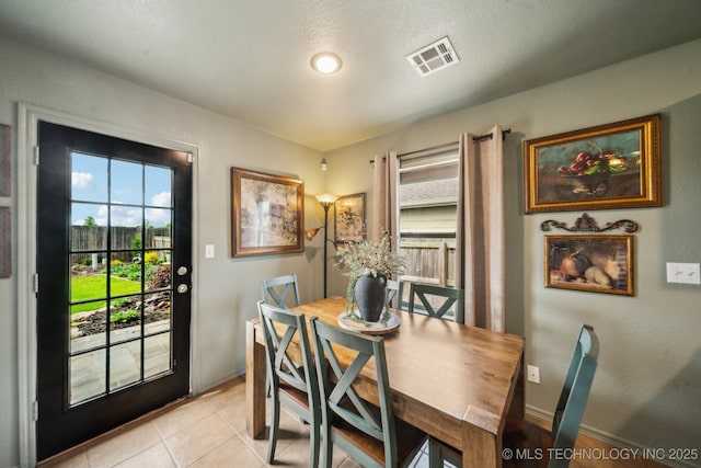 dining room with plenty of natural light, light tile patterned floors, and baseboards