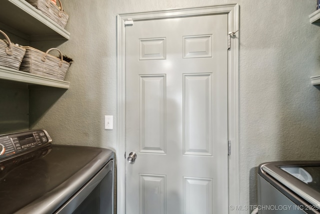 laundry area with washing machine and clothes dryer and a textured wall