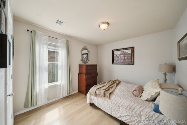 bedroom featuring light wood finished floors and baseboards