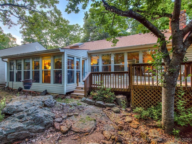rear view of property with a sunroom and a deck