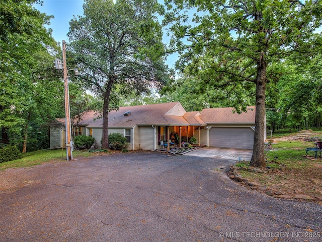 ranch-style house with asphalt driveway, a garage, and a porch