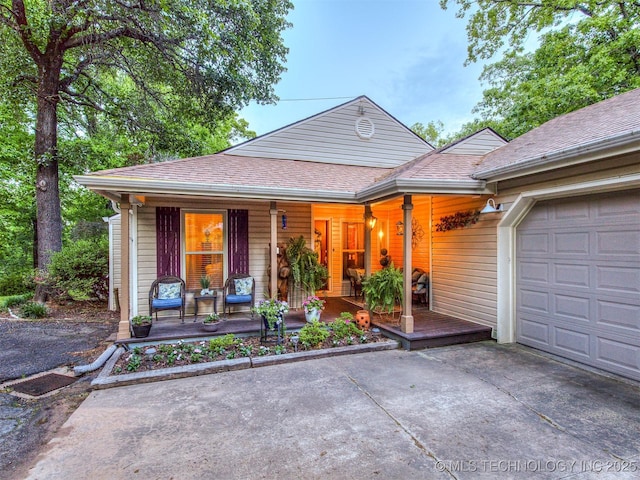 view of front of home featuring covered porch, concrete driveway, a garage, and a shingled roof