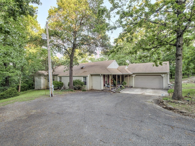 single story home featuring asphalt driveway, an attached garage, and covered porch