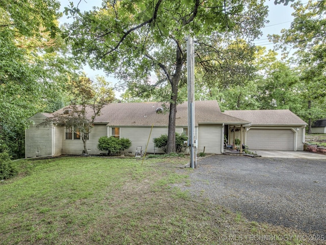 back of house with a garage, gravel driveway, and a lawn