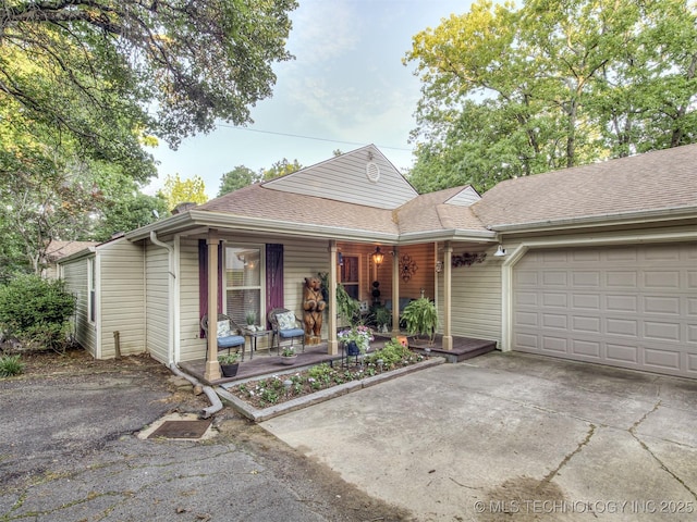 view of front of house with covered porch, concrete driveway, a garage, and a shingled roof
