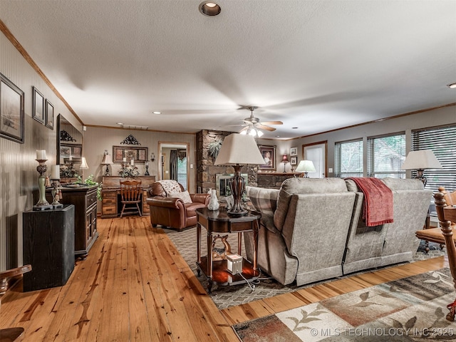 living area featuring ornamental molding, light wood-style floors, a ceiling fan, a textured ceiling, and recessed lighting