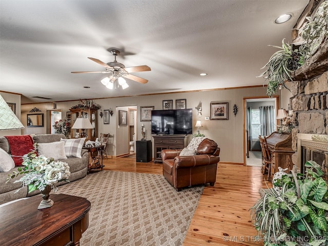 living area featuring light wood-style floors, ceiling fan, baseboards, recessed lighting, and a fireplace