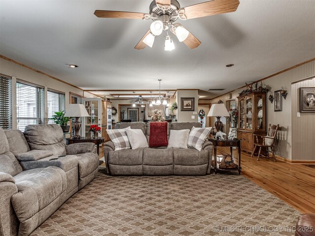 living area featuring crown molding, light wood-style flooring, a ceiling fan, and baseboards