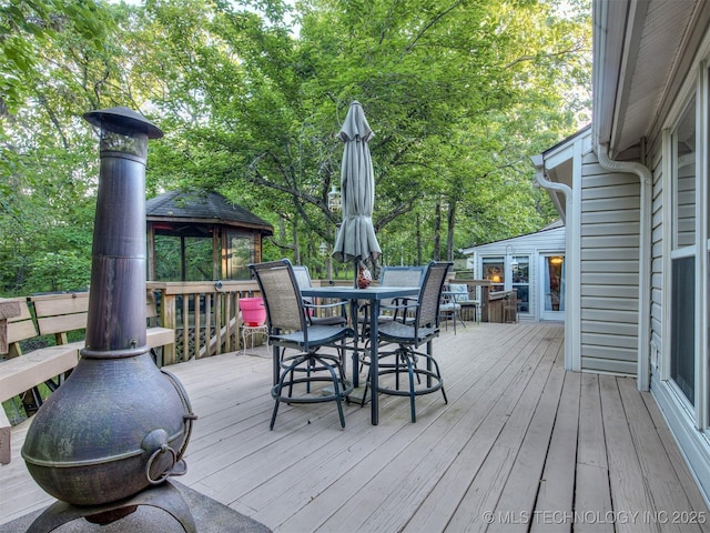 wooden terrace featuring a gazebo and outdoor dining space