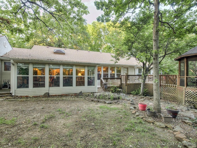 back of property featuring a sunroom, a deck, and roof with shingles