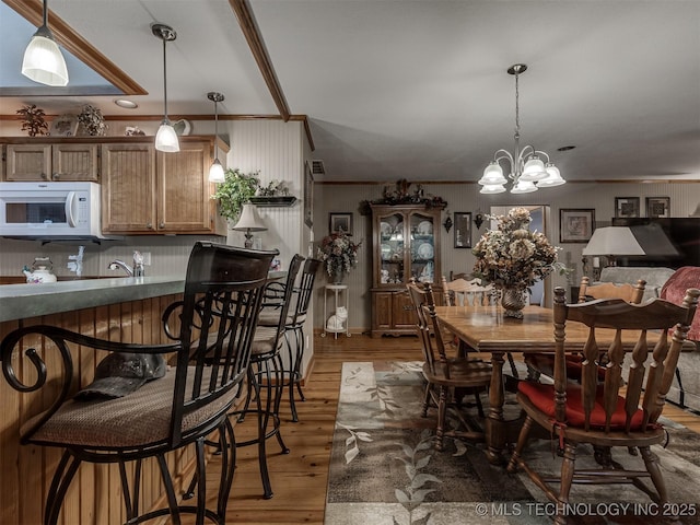 dining space with ornamental molding, light wood-style floors, and a chandelier
