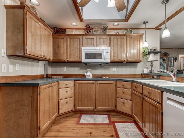 kitchen with white appliances, a sink, dark countertops, a skylight, and ornamental molding