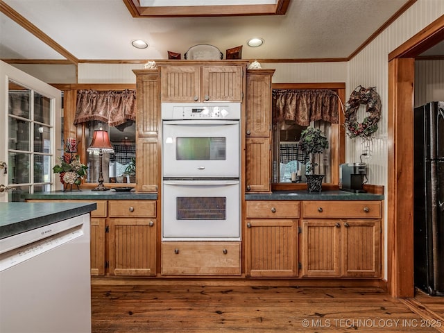 kitchen with white double oven, dishwasher, freestanding refrigerator, crown molding, and dark countertops