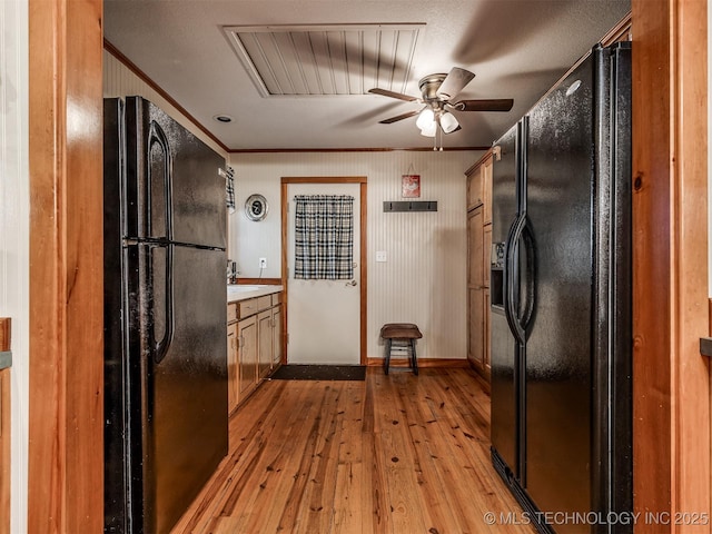 kitchen with black refrigerator with ice dispenser, freestanding refrigerator, crown molding, ceiling fan, and light wood finished floors