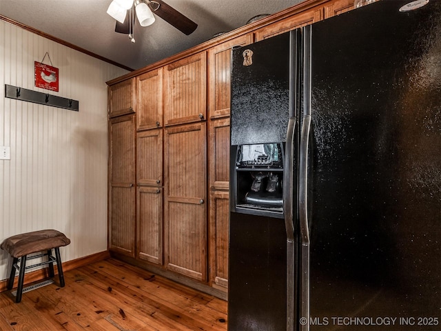 kitchen featuring black refrigerator with ice dispenser, ornamental molding, brown cabinetry, hardwood / wood-style floors, and ceiling fan