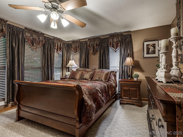 bedroom with light colored carpet, a ceiling fan, and baseboards