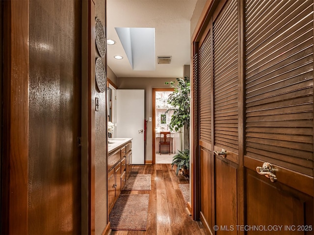 corridor with dark wood-type flooring, recessed lighting, and baseboards