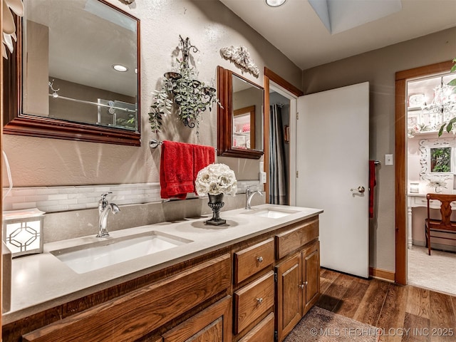 bathroom with wood finished floors, backsplash, double vanity, and recessed lighting