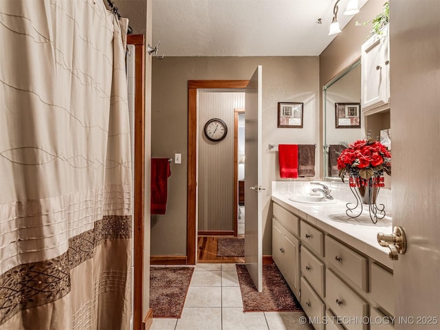 full bathroom featuring vanity, tile patterned flooring, a shower with curtain, baseboards, and a textured ceiling