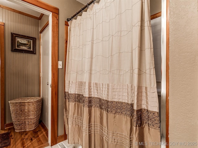 full bathroom featuring wood finished floors, a textured wall, and curtained shower