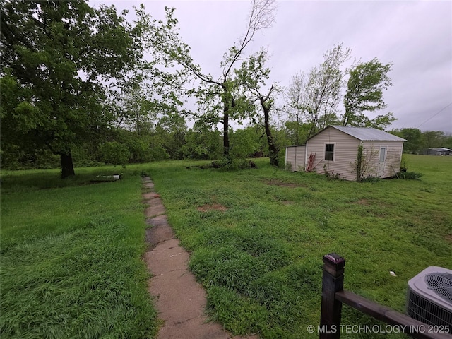 view of green lawn with cooling unit and an outbuilding