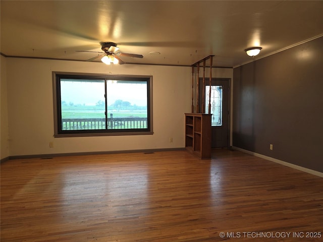 empty room featuring a ceiling fan, wood finished floors, and baseboards