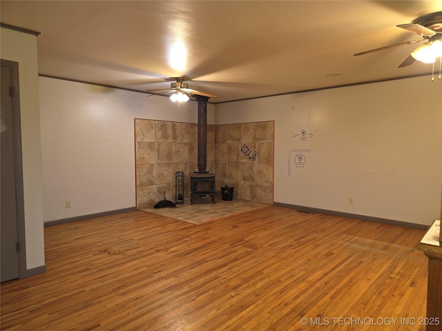 unfurnished living room with a ceiling fan, a wood stove, and wood-type flooring