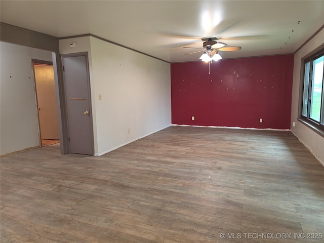 unfurnished room featuring a ceiling fan, wood finished floors, baseboards, and ornamental molding