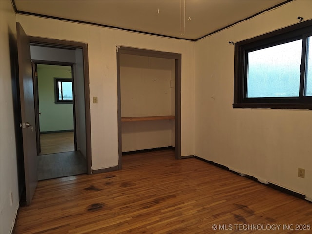unfurnished bedroom with wood finished floors, a closet, and baseboards
