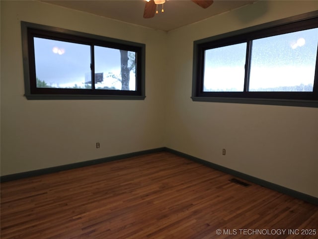 spare room with plenty of natural light, dark wood-style flooring, and baseboards