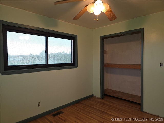 unfurnished bedroom with wood finished floors, baseboards, and a ceiling fan