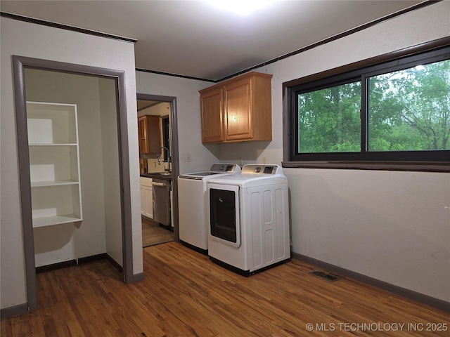 laundry room featuring cabinet space, separate washer and dryer, dark wood-style flooring, and baseboards