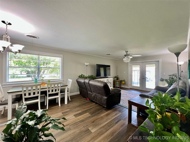 205 NE 1st St, Kingston, OK 73439 - living area with wood finished floors, crown molding, a chandelier, french doors, and a textured ceiling