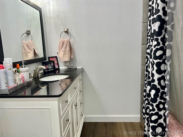 205 NE 1st St, Kingston, OK 73439 - bathroom featuring wood finished floors, vanity, baseboards, and a shower with shower curtain
