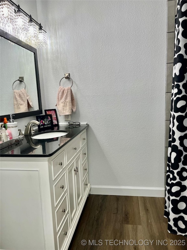 205 NE 1st St, Kingston, OK 73439 - full bathroom with wood finished floors, vanity, baseboards, and a shower with curtain