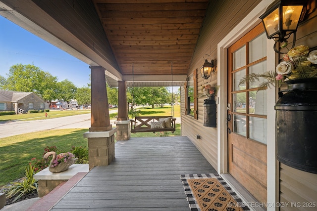deck with a porch and a yard