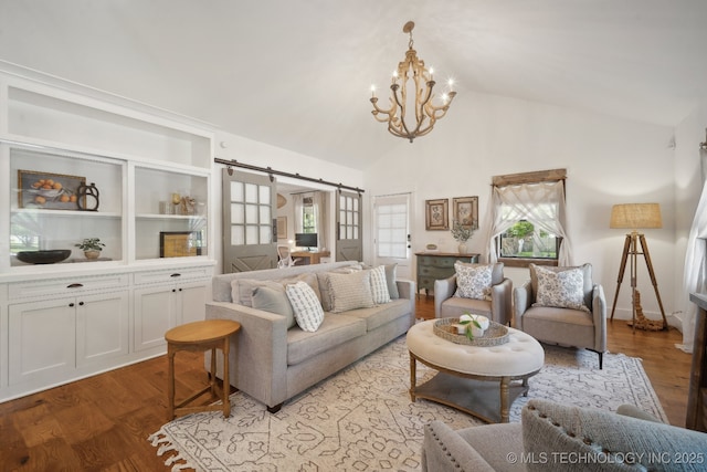 living area with a barn door, a chandelier, plenty of natural light, light wood-style flooring, and high vaulted ceiling