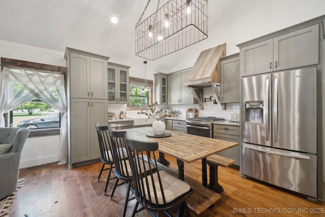 kitchen featuring appliances with stainless steel finishes, gray cabinets, high vaulted ceiling, and custom range hood