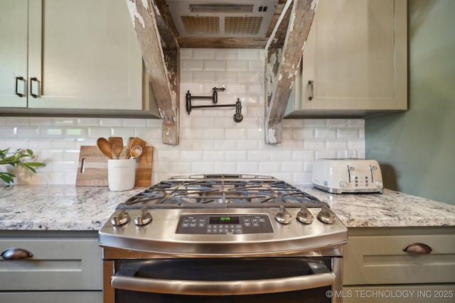 kitchen featuring stainless steel gas stove, range hood, tasteful backsplash, and light stone counters