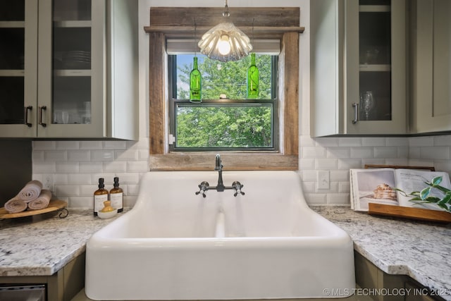 kitchen featuring a sink, glass insert cabinets, and decorative backsplash